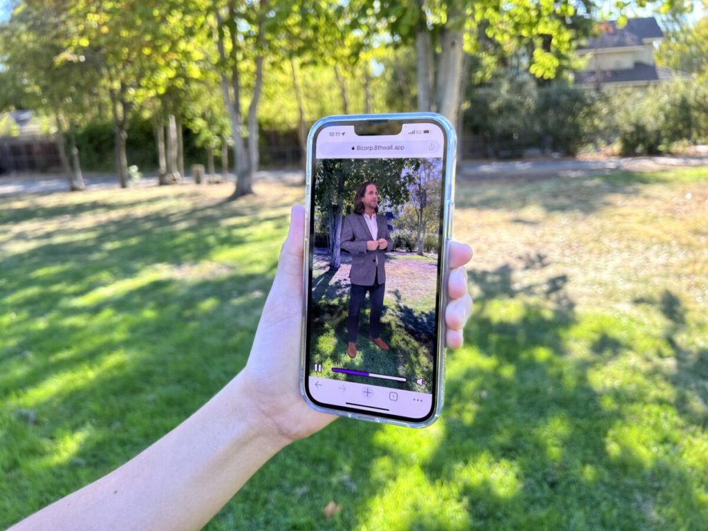 Hand holding smartphone that displays AR hologram